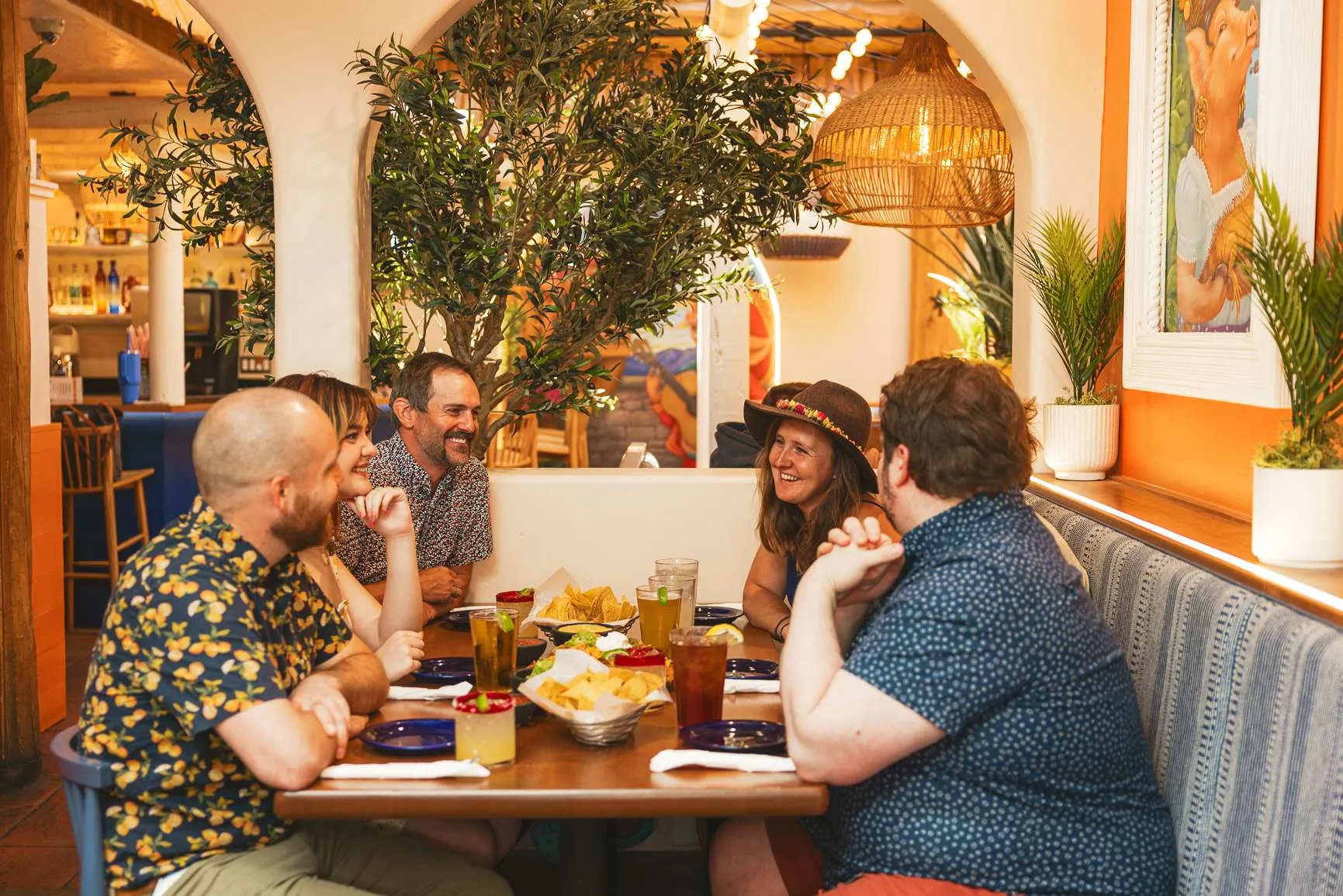 Group of friends enjoying a meal at a colorful restaurant, featuring plates of nachos and drinks, in a vibrant dining atmosphere, reflecting the dining options in Jackson Hole.