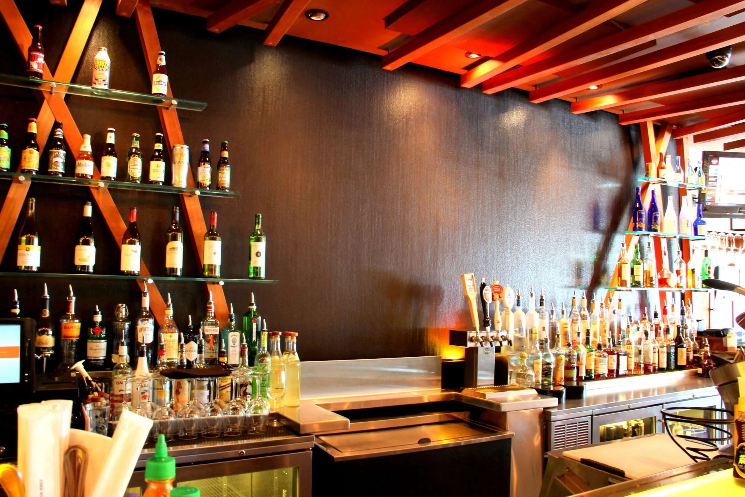 Bar setup featuring a variety of liquor bottles on shelves, a modern design, and a sleek counter, relevant to dining experiences in Jackson Hole.