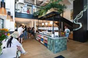 Interior of Snake River Roasting Company café featuring a bustling counter with baristas, customers waiting in line, and vibrant decor, highlighting the community atmosphere and specialty coffee offerings.