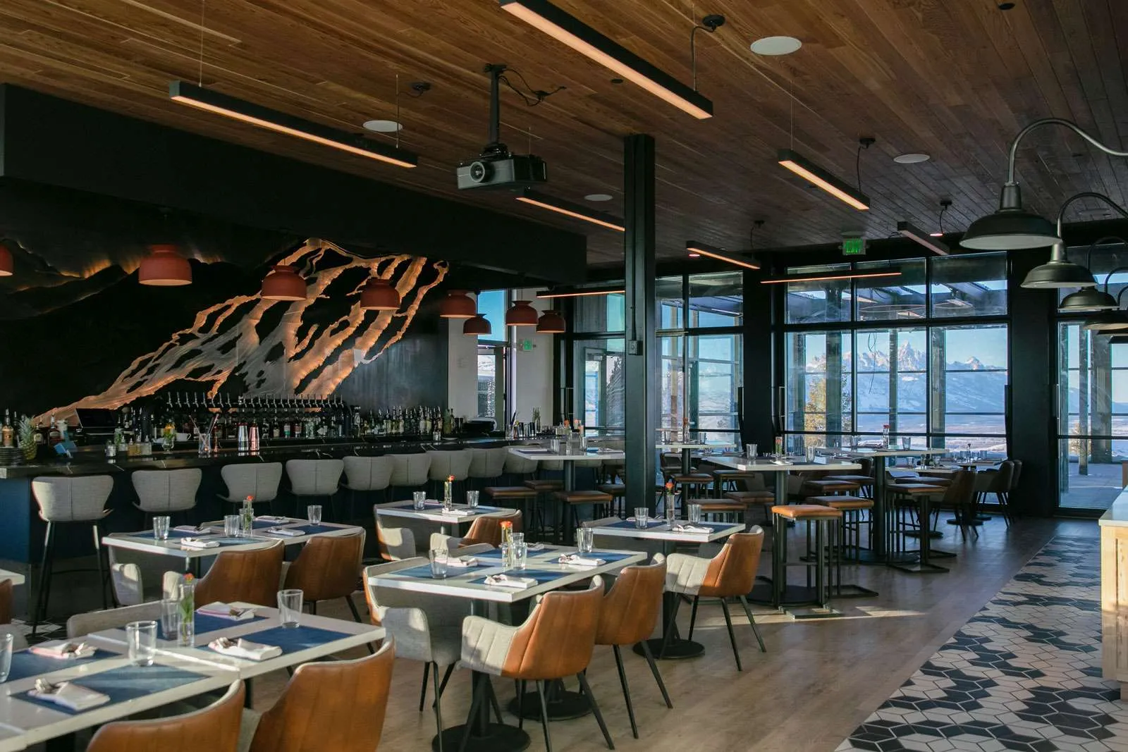 Modern restaurant interior featuring panoramic mountain views, stylish seating, and a bar area, highlighting Snow King Mountain Dining & Catering.