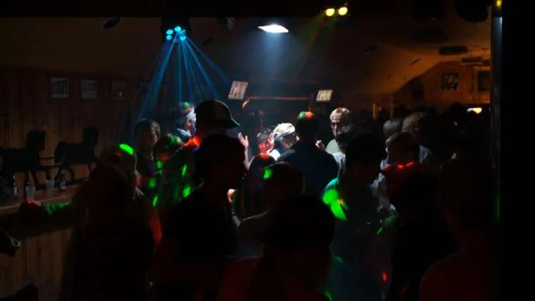 Crowd dancing at Stagecoach Bar during disco night, colorful lights illuminating a lively atmosphere.
