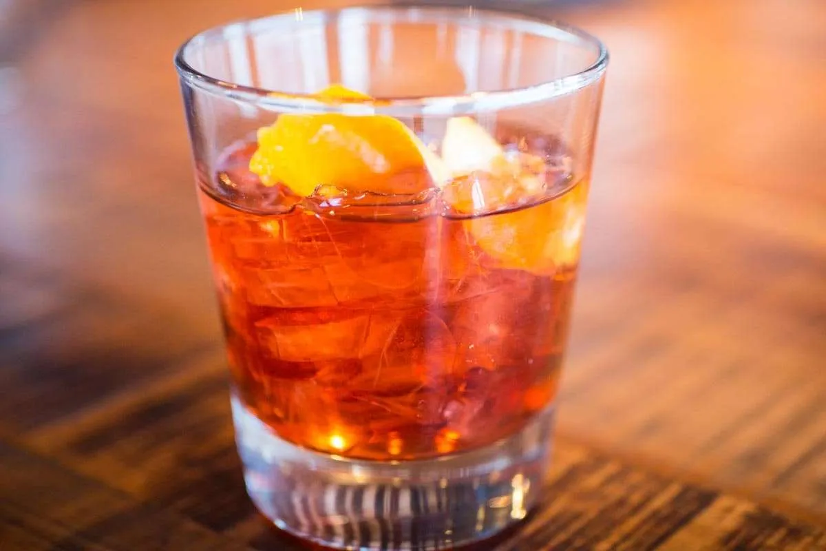 Cocktail with orange garnish in a glass, featured in a dining guide for Jackson Hole restaurants and bars.