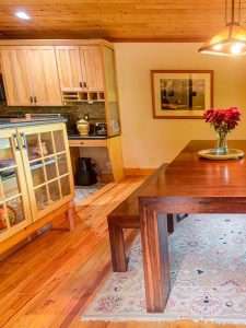 Modern kitchen and dining area featuring wooden cabinetry, a large dining table, and a floral centerpiece, illustrating a clean and inviting space for residential cleaning services in Jackson Hole.