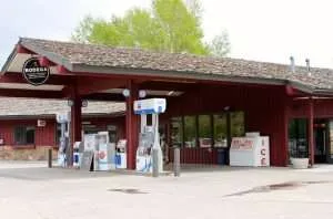 Bodega store exterior in Teton Village featuring a red building with a sloped roof, signage, and displays for groceries, beverages, and ice, catering to travelers and locals.