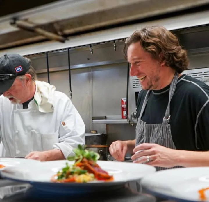 Chefs collaborating in a restaurant kitchen, preparing inventive dishes for the Fine Dining Restaurant Group in Jackson Hole.