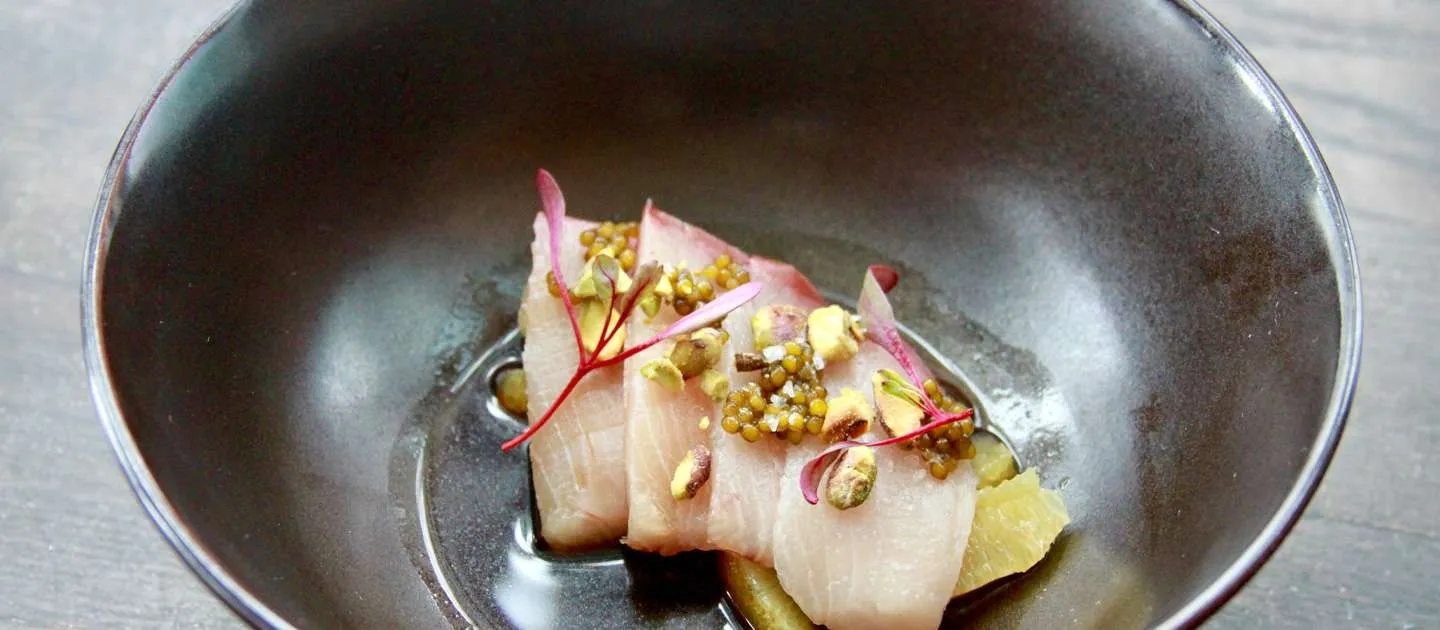 Fresh fish dish with garnishes, served in a stylish bowl, highlighting inventive small plates at a modern American restaurant in Jackson Hole.